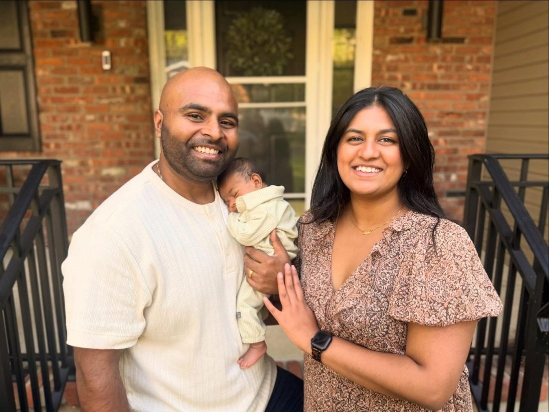 Jaise John with his wife and baby son outside their home